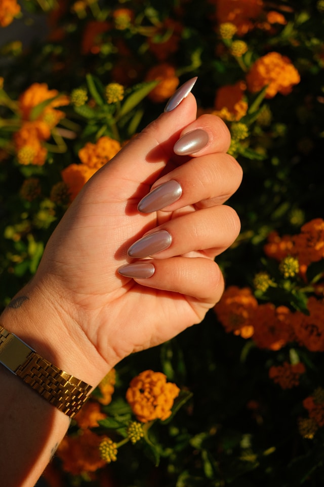 Silver chrome manicure against marigold flowers